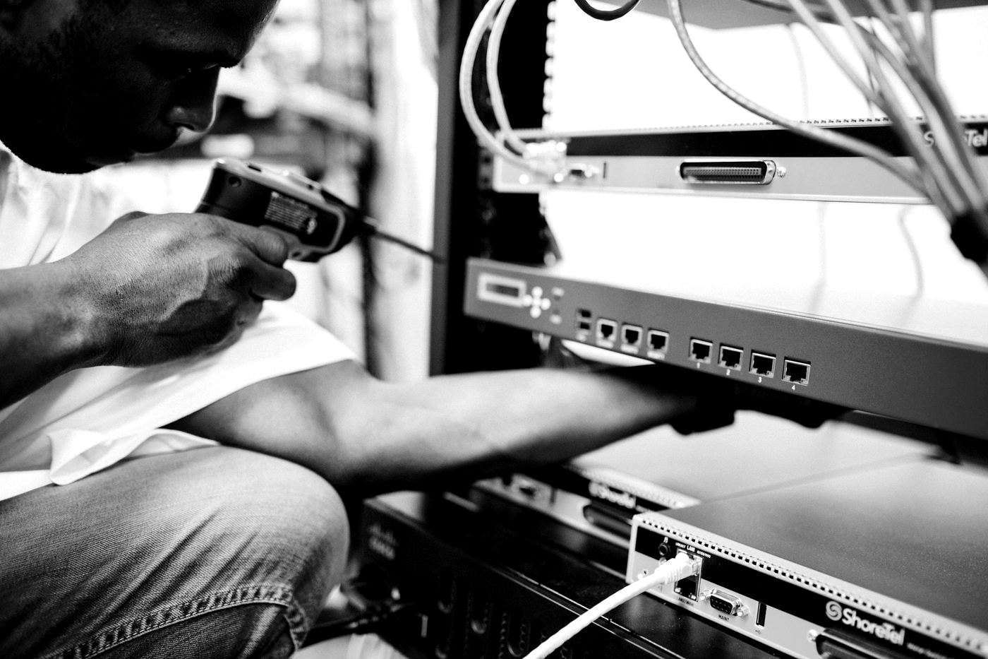 A network engineer working on telecoms equipment in a server rack